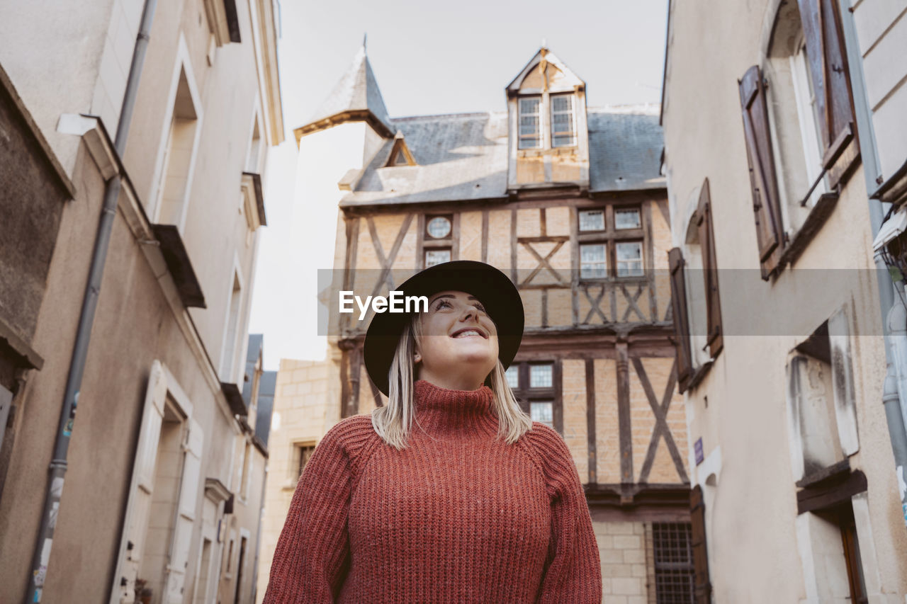 Low angle view of young woman standing against buildings in city