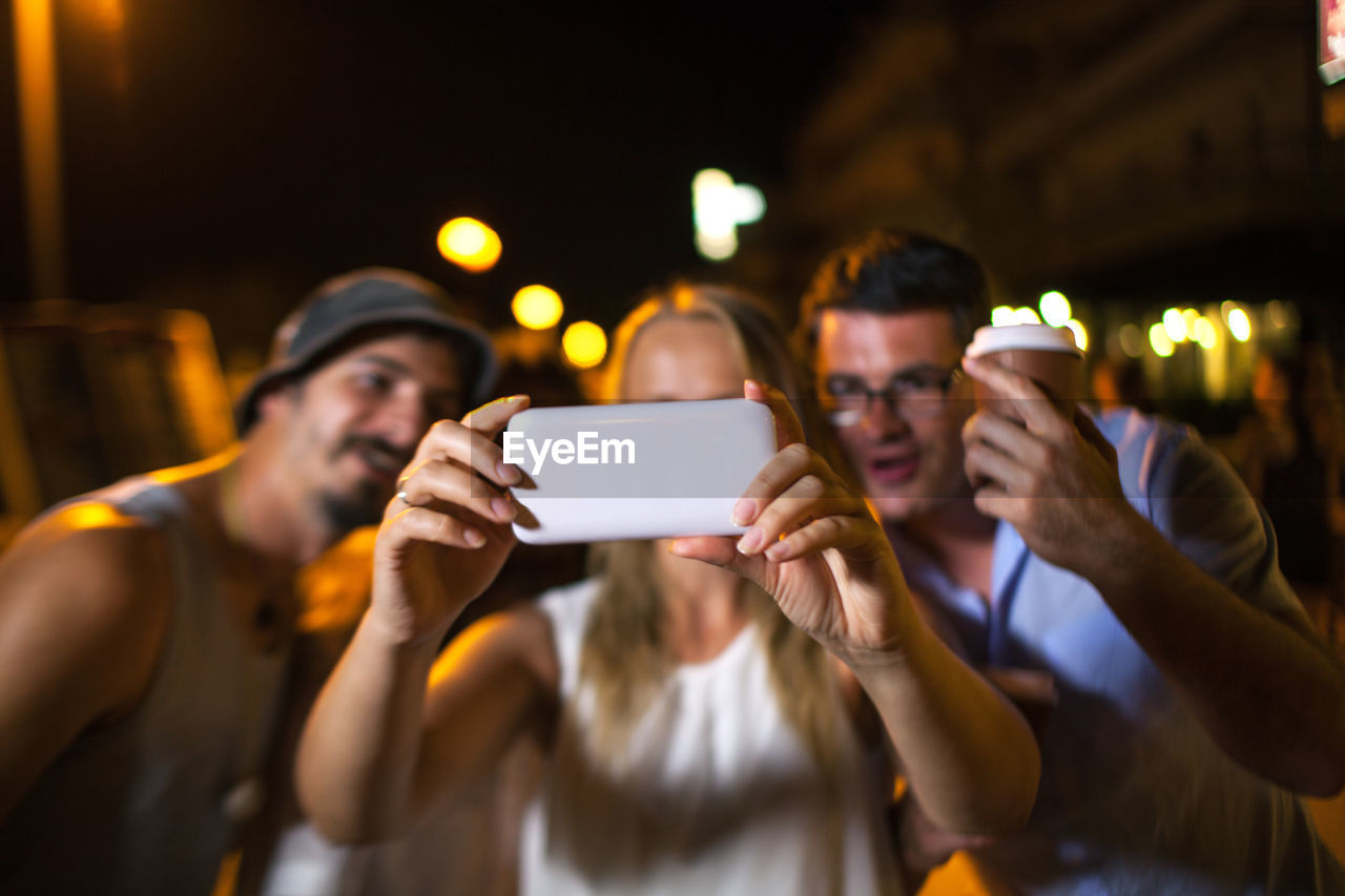 Cheerful friends taking selfie at night