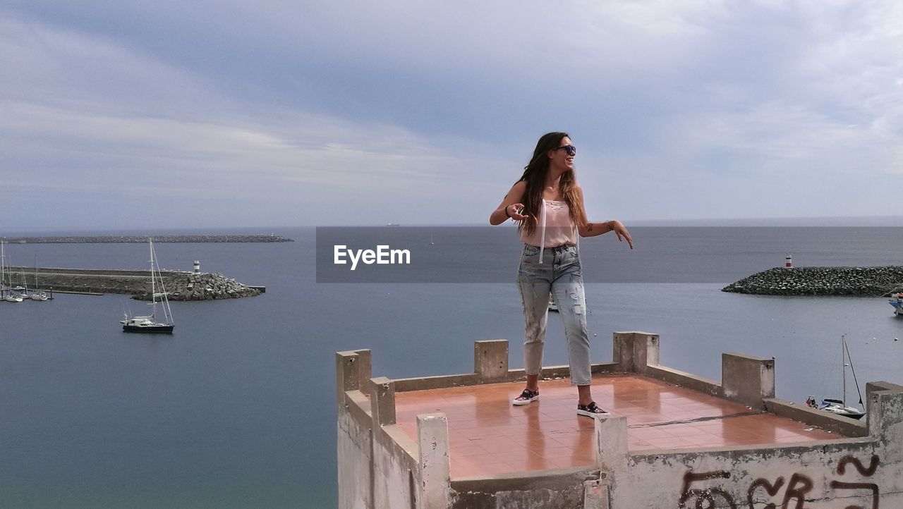 Smiling young woman standing at observation point by sea