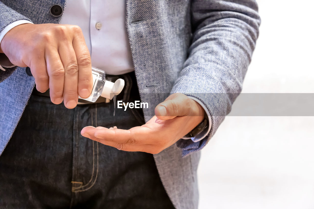 Man using wash hand sanitizer gel dispenser adopting to prevent the diffusion of the coronavirus.