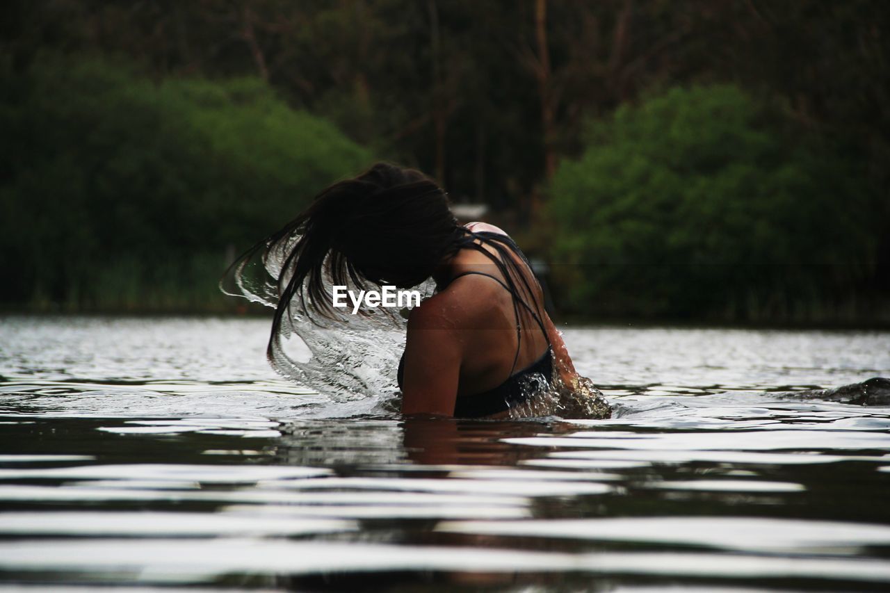 REAR VIEW OF WOMAN IN WATER AT PARK