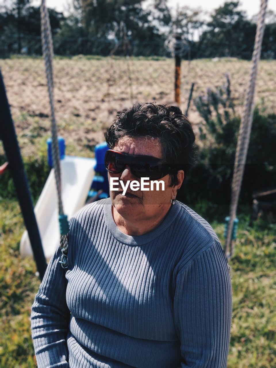 Woman wearing sunglasses while sitting on swing