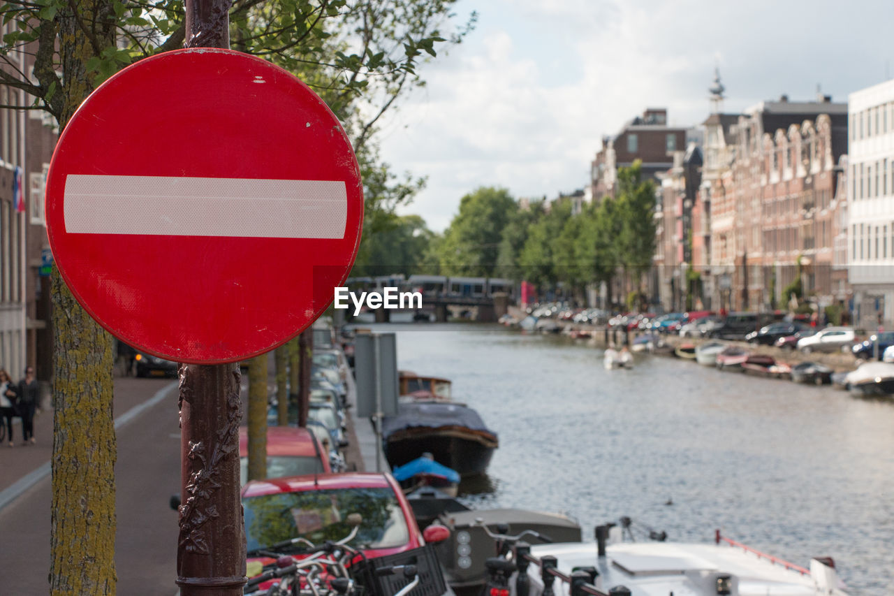 Red do not enter sign on road sign by canal in city