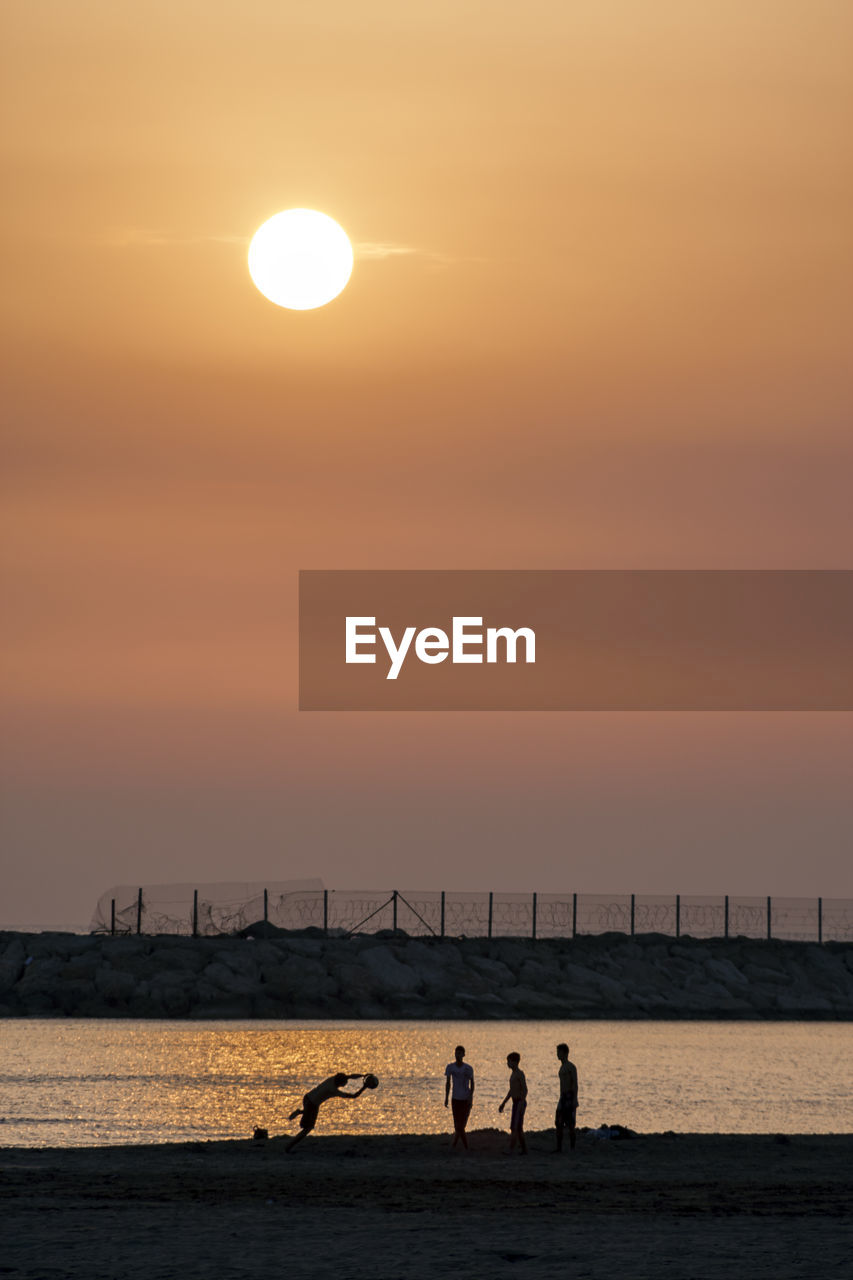 Men at beach during sunset