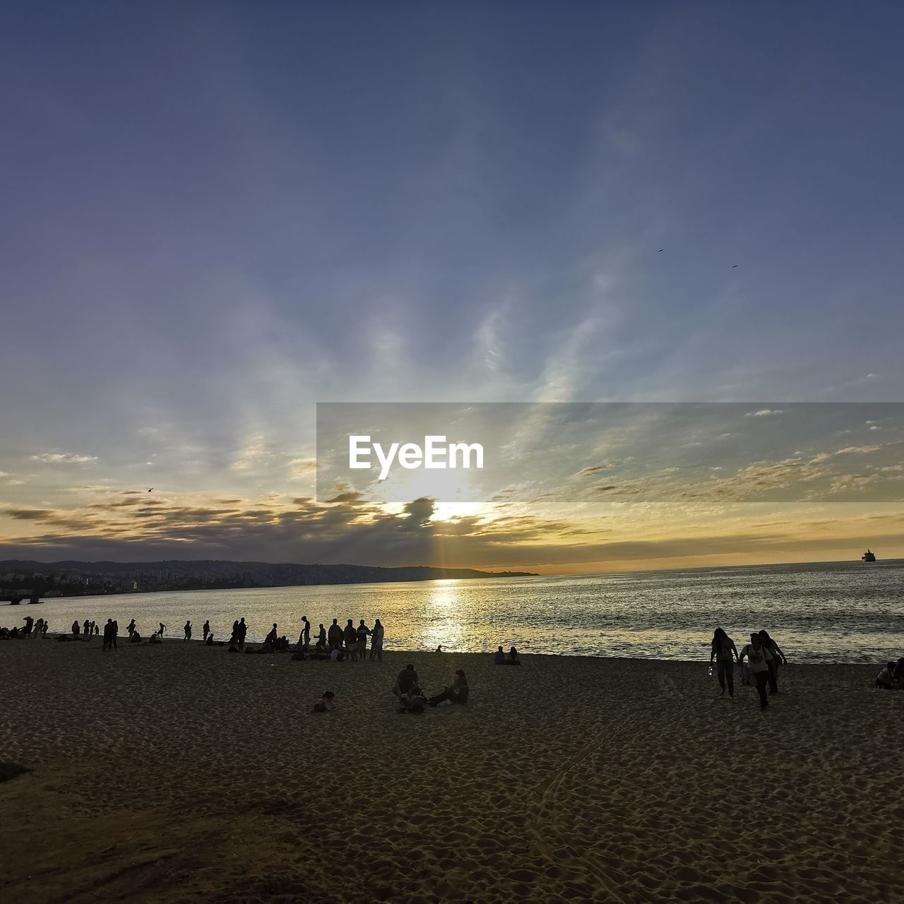 People on beach against sky during sunset