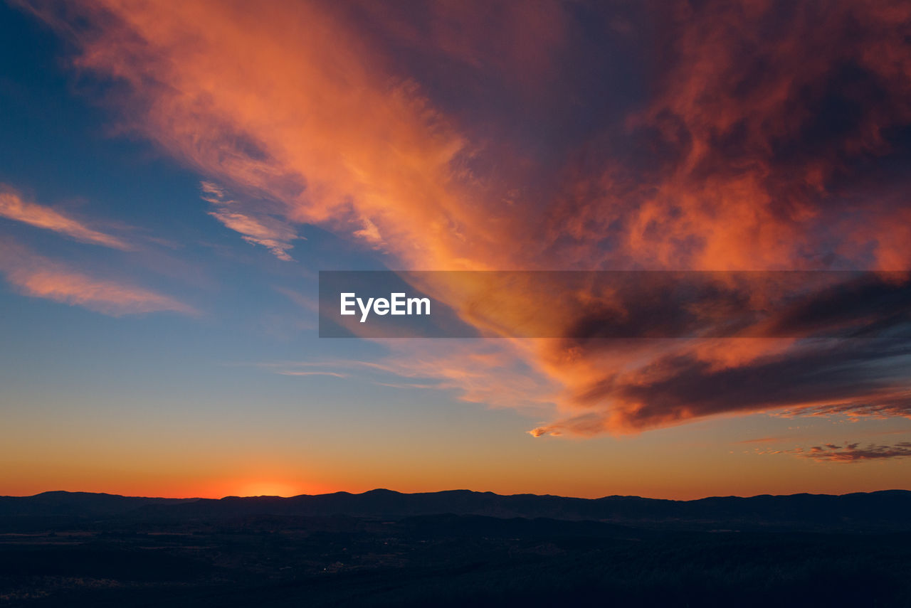 Scenic view of silhouette landscape against orange sky