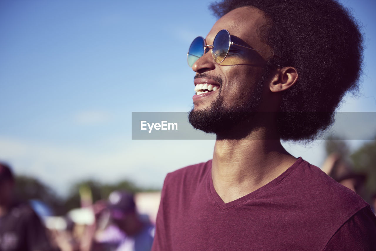 Close-up of smiling young man wearing sunglasses against sky