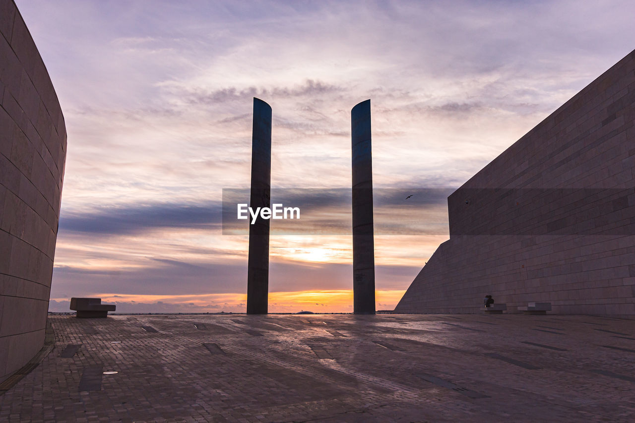 Scenic view of sea by buildings against sky during sunset