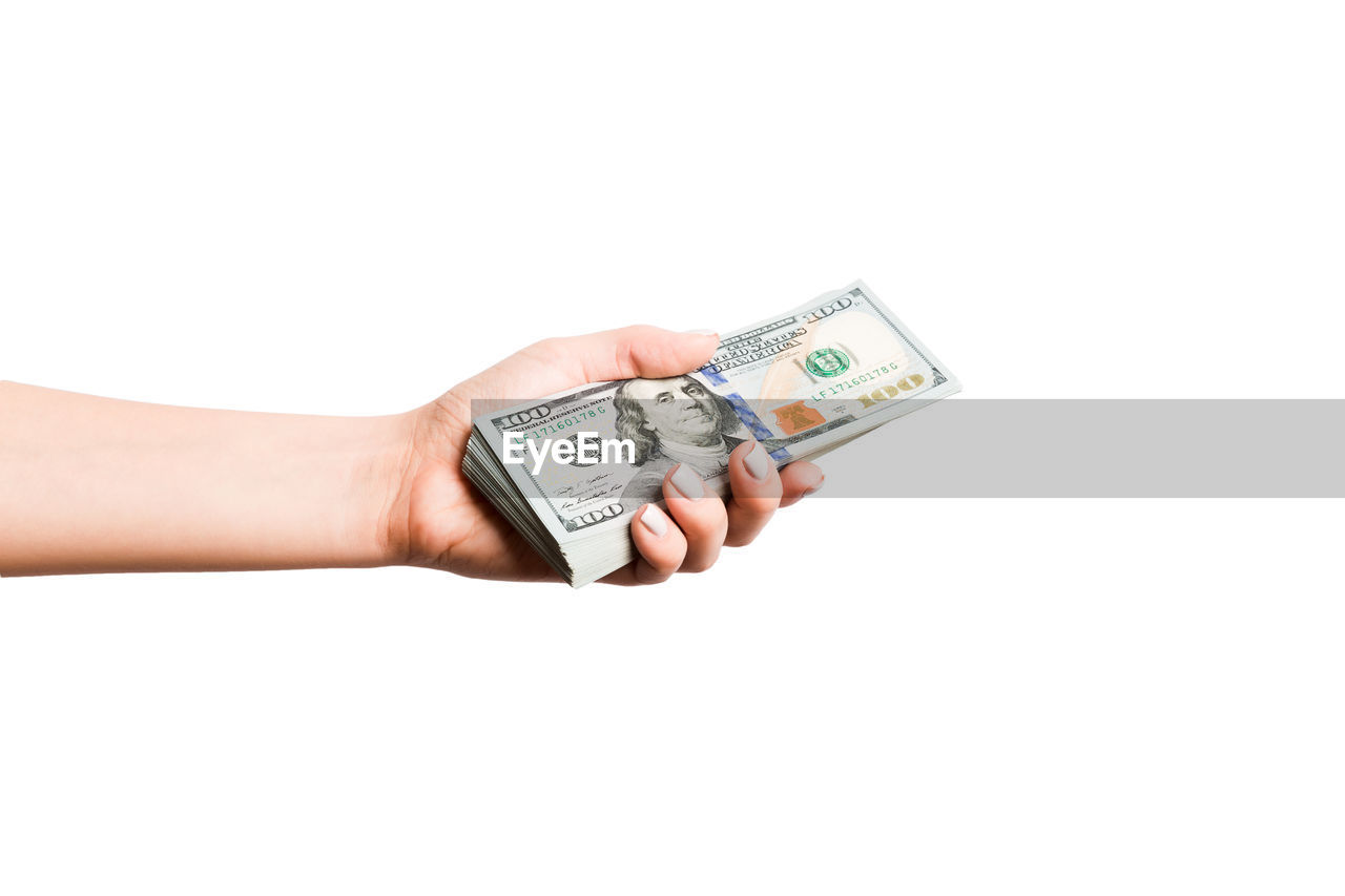 Cropped hand holding paper currencies against white background