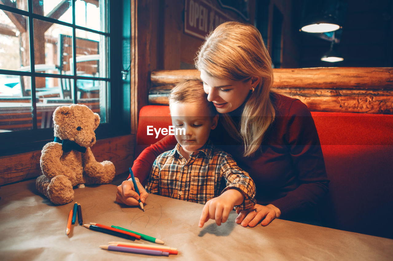 Mother and son sitting by table