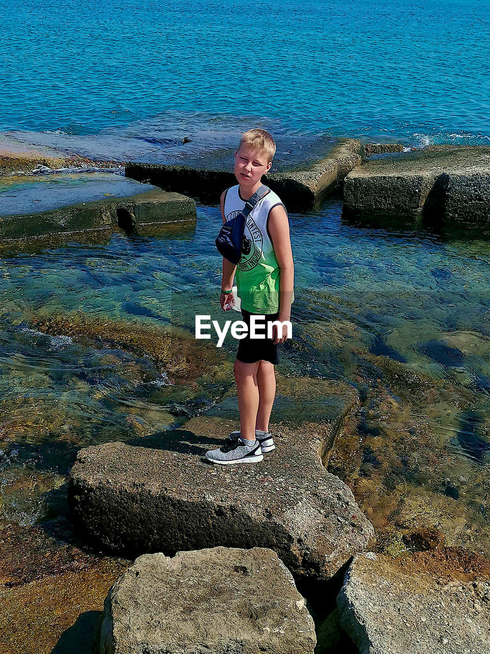 Boy standing on rock at sea shore