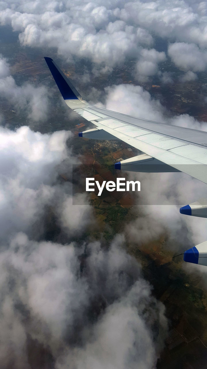 AIRPLANE WING AGAINST CLOUDY SKY