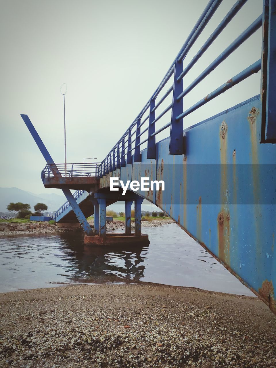 BRIDGE OVER CALM RIVER AGAINST SKY