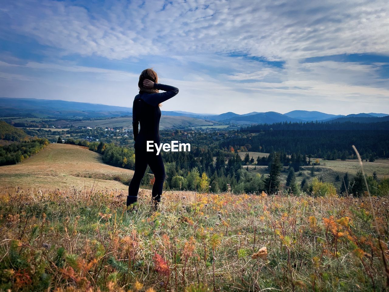 Full body shot of woman wearing sports clothes and looking at the mountains in front of her