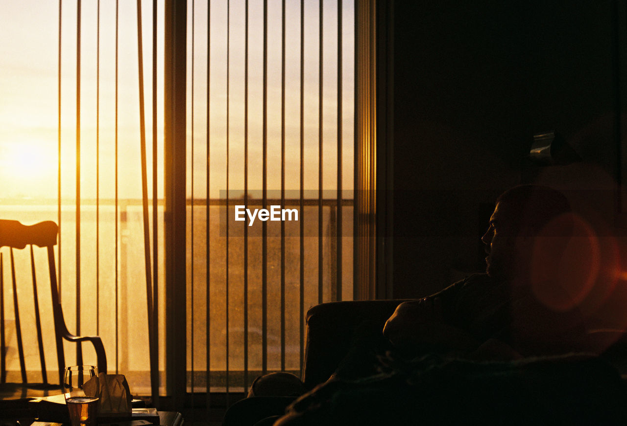 Man sitting on chair by window at home