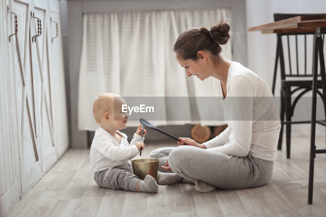 Mother plays with her son baby on the floor in a real bright interior, the concept of motherhood 