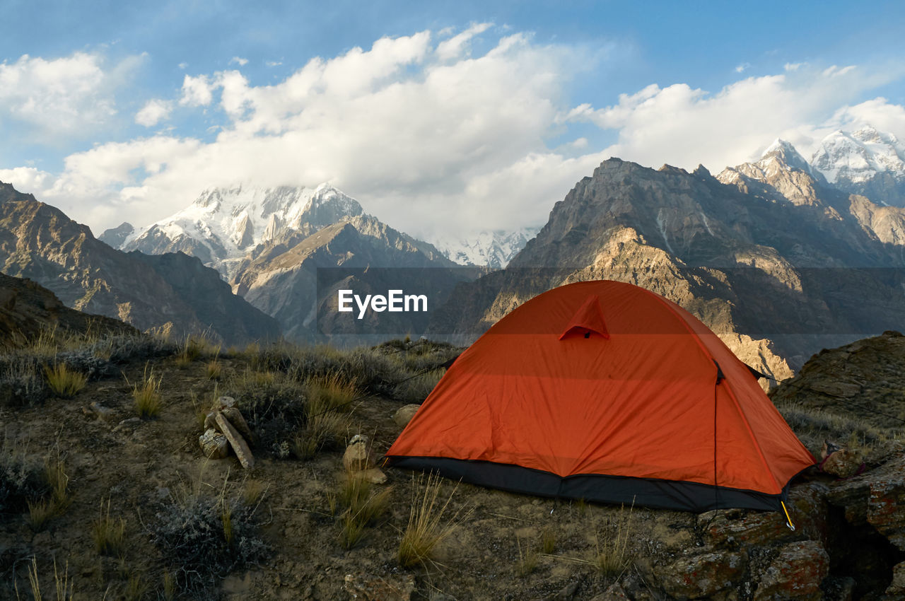 TENT IN FIELD AGAINST MOUNTAINS