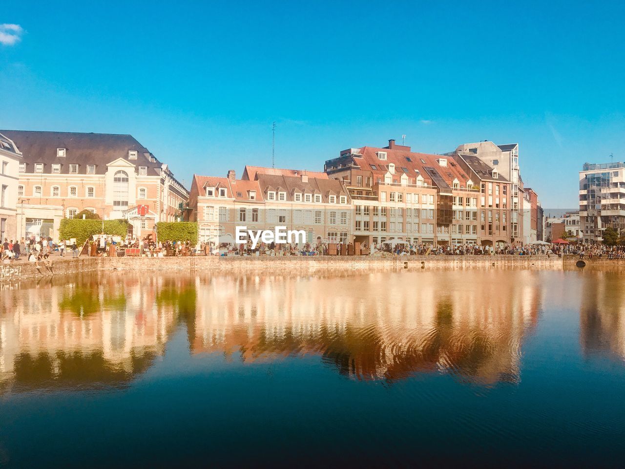 Reflection of buildings in lake against blue sky