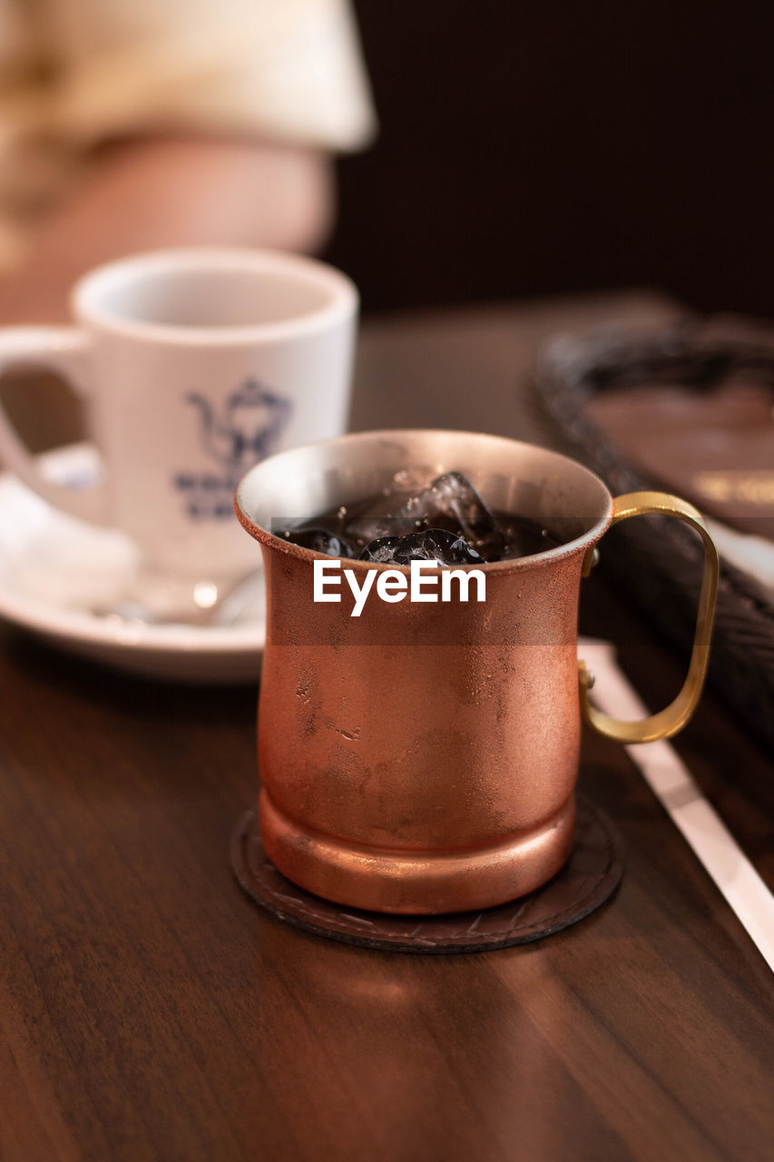 food and drink, cup, coffee cup, drink, mug, coffee, hot drink, food, refreshment, table, wood, indoors, crockery, kitchen utensil, no people, tea, brown, spoon, close-up, tea cup, chocolate, saucer, freshness, focus on foreground, studio shot