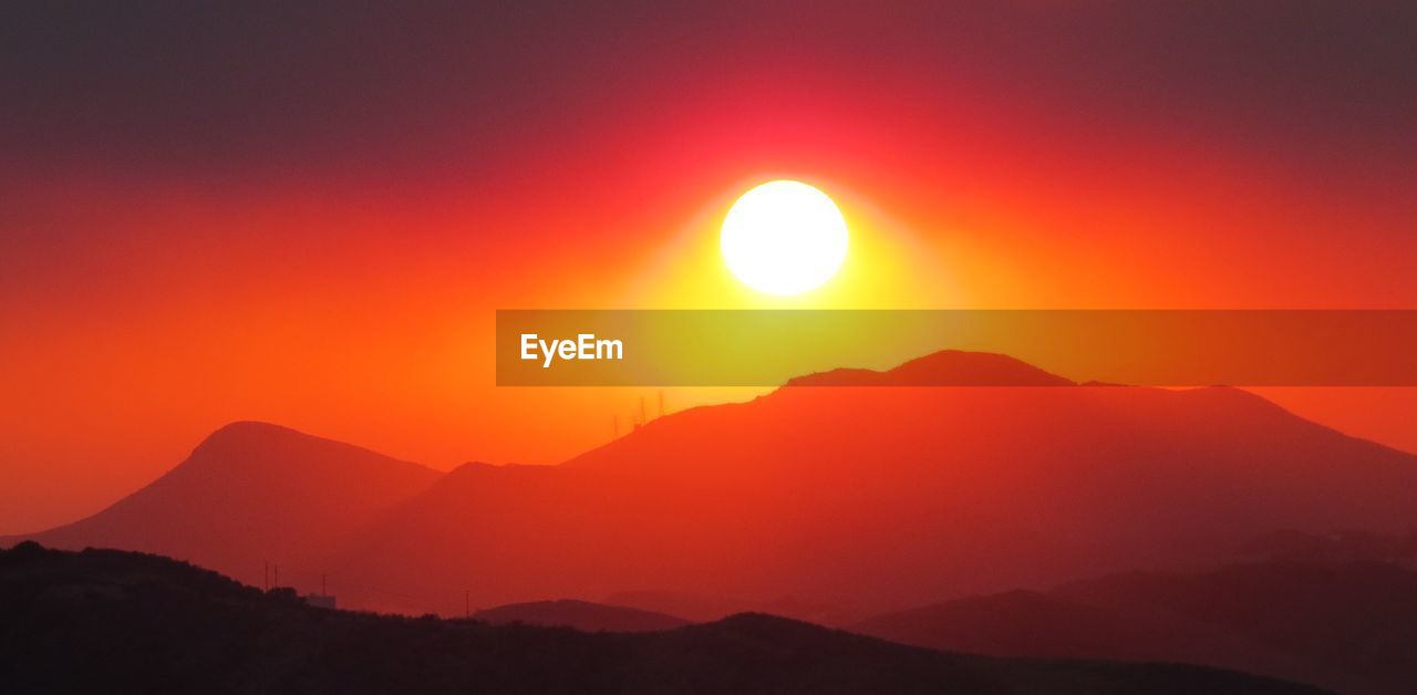 SCENIC VIEW OF SILHOUETTE MOUNTAINS AGAINST ORANGE SKY