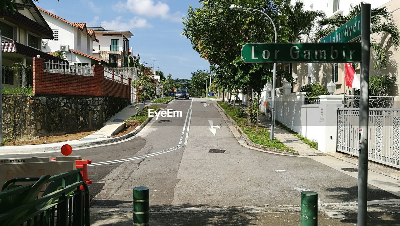 Road sign by building against sky