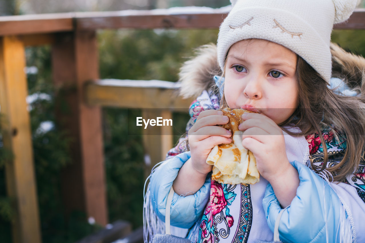 Cute girl eating food outdoors