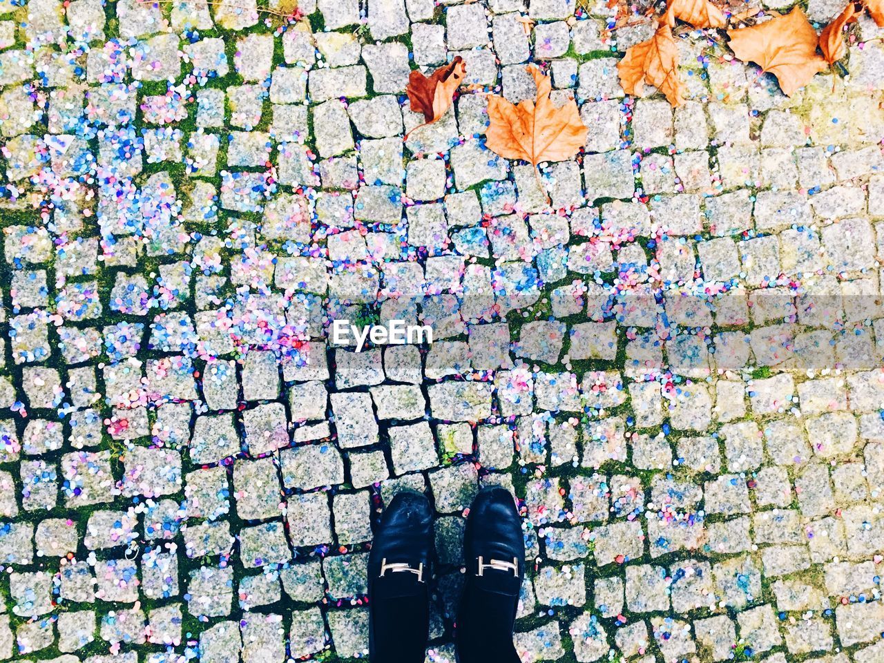Low section of woman on road amidst confetti