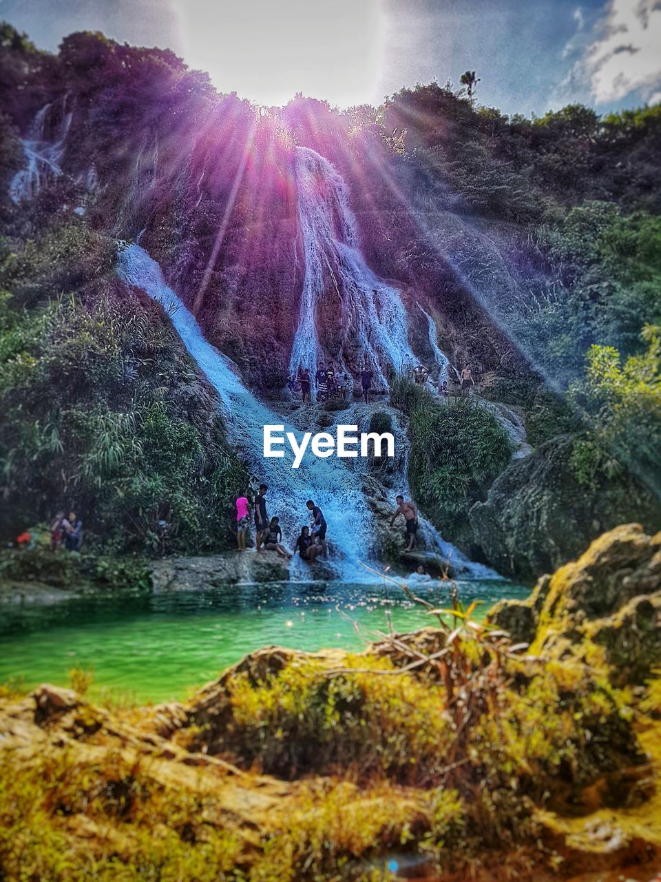 People at waterfall against sky