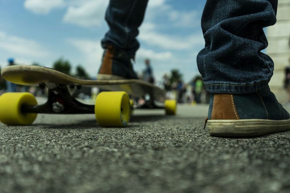 Low section of man with skateboard on street