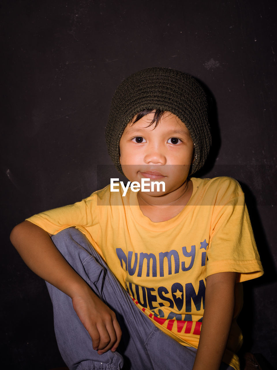 Portrait of cute boy wearing hat against black background