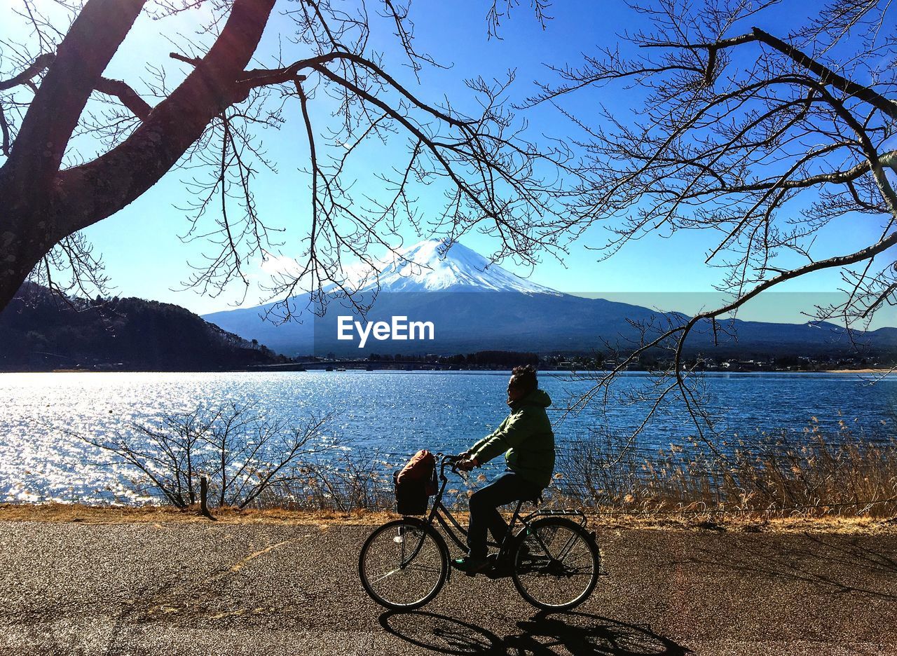 Side view of man riding bicycle by lake