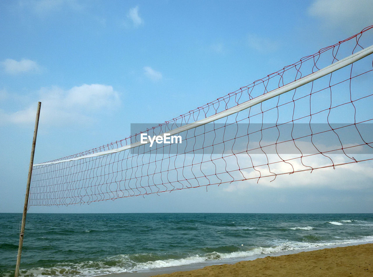 Volleyball net at beach against sky