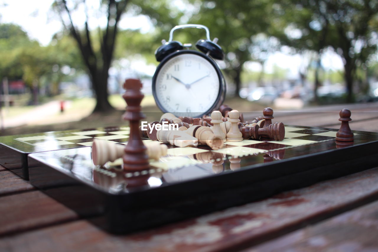 Close-up of clock with chess board on table