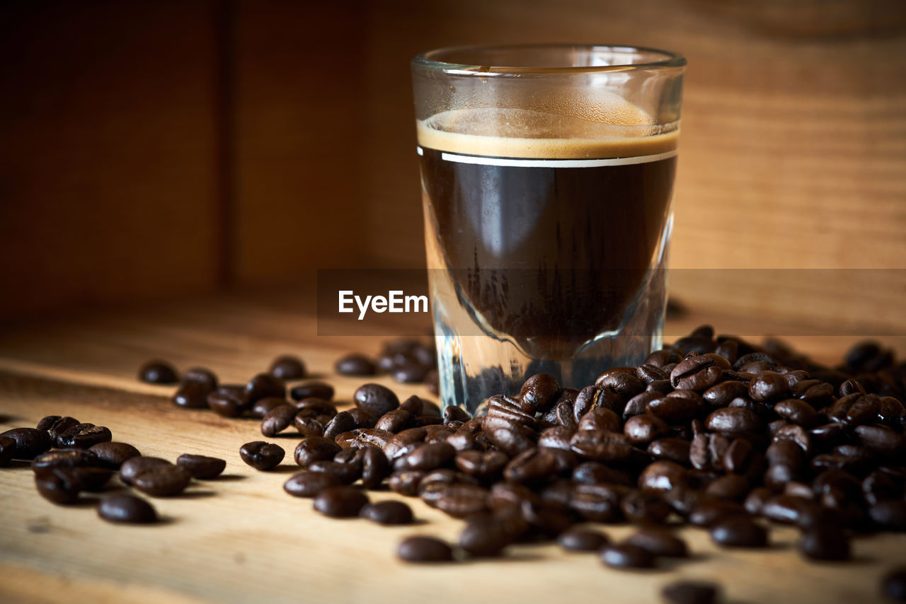 Black coffee with roasted beans on table