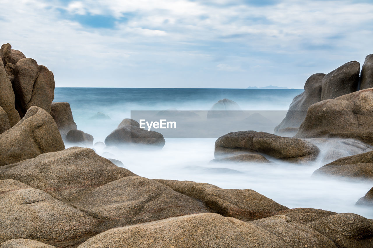 Scenic view of rocks in sea against sky