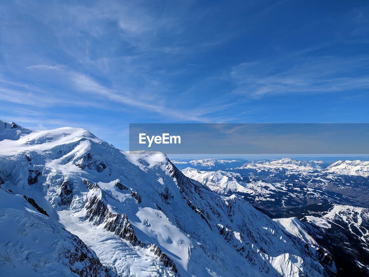 Scenic view of snowcapped mountains against blue sky