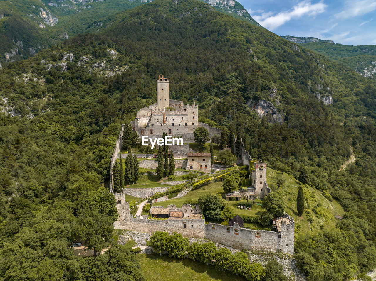 architecture, plant, built structure, mountain, tree, building exterior, history, the past, building, travel destinations, nature, mountain range, travel, land, scenics - nature, tourism, landscape, château, aerial photography, environment, no people, high angle view, ancient, sky, beauty in nature, village, green, religion, outdoors, day, town, castle, old, house, lush foliage, tranquility, foliage, forest, place of worship, city, fort, rural area, residential district, cloud, valley, belief, tranquil scene, spirituality, growth