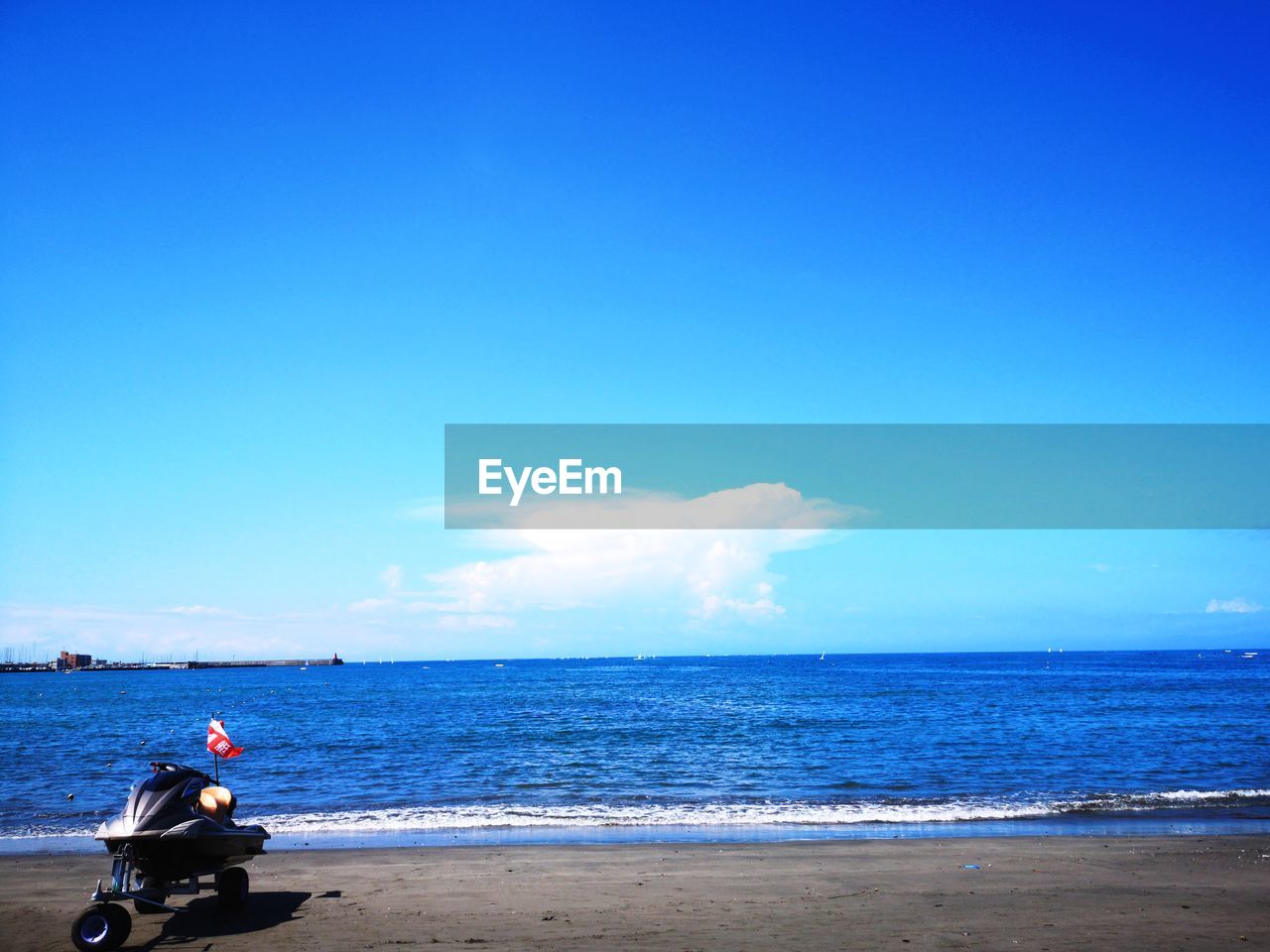 Scenic view of jet boat on beach against blue sky