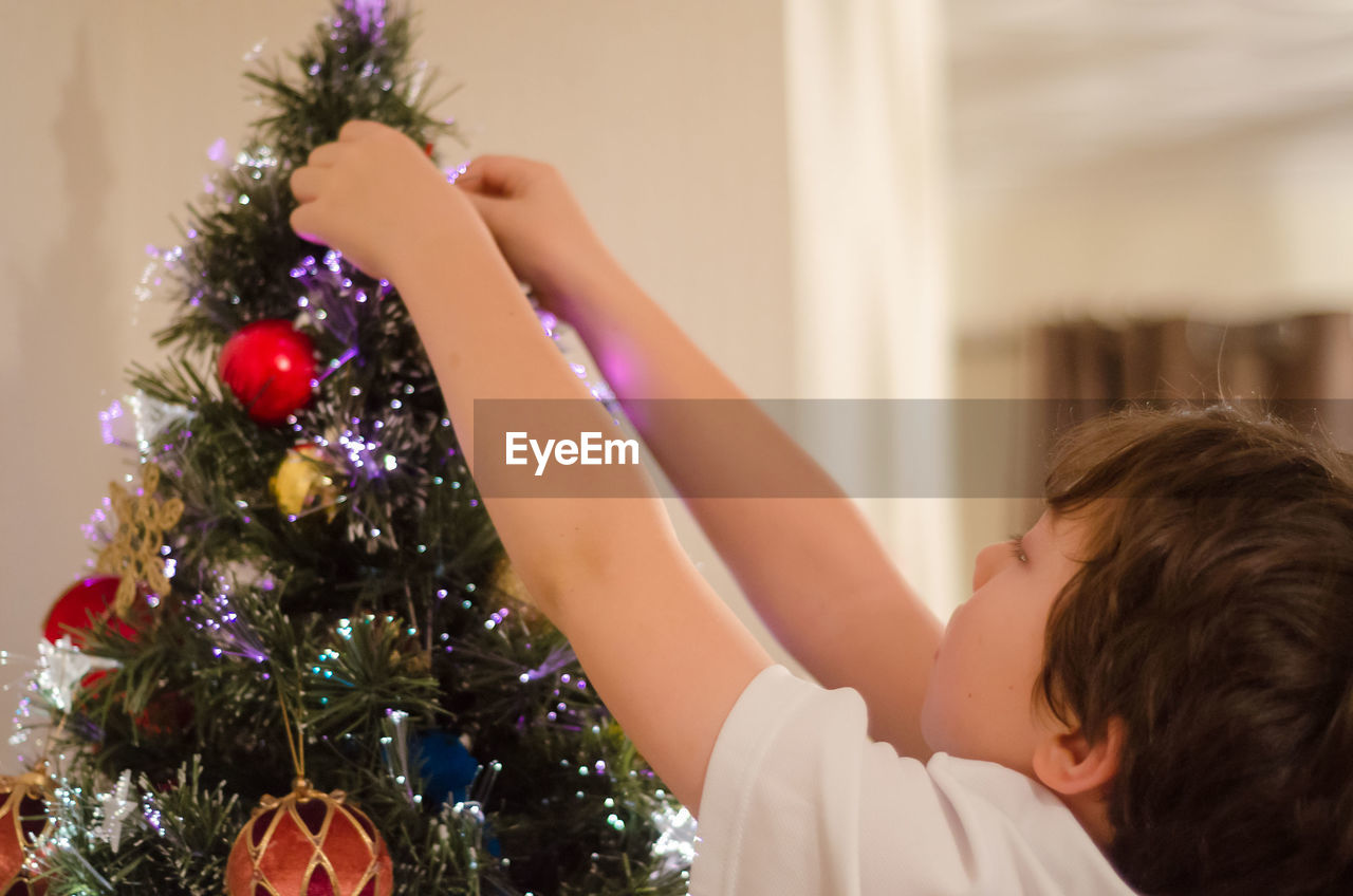 Close-up of boy decorating christmas tree at home