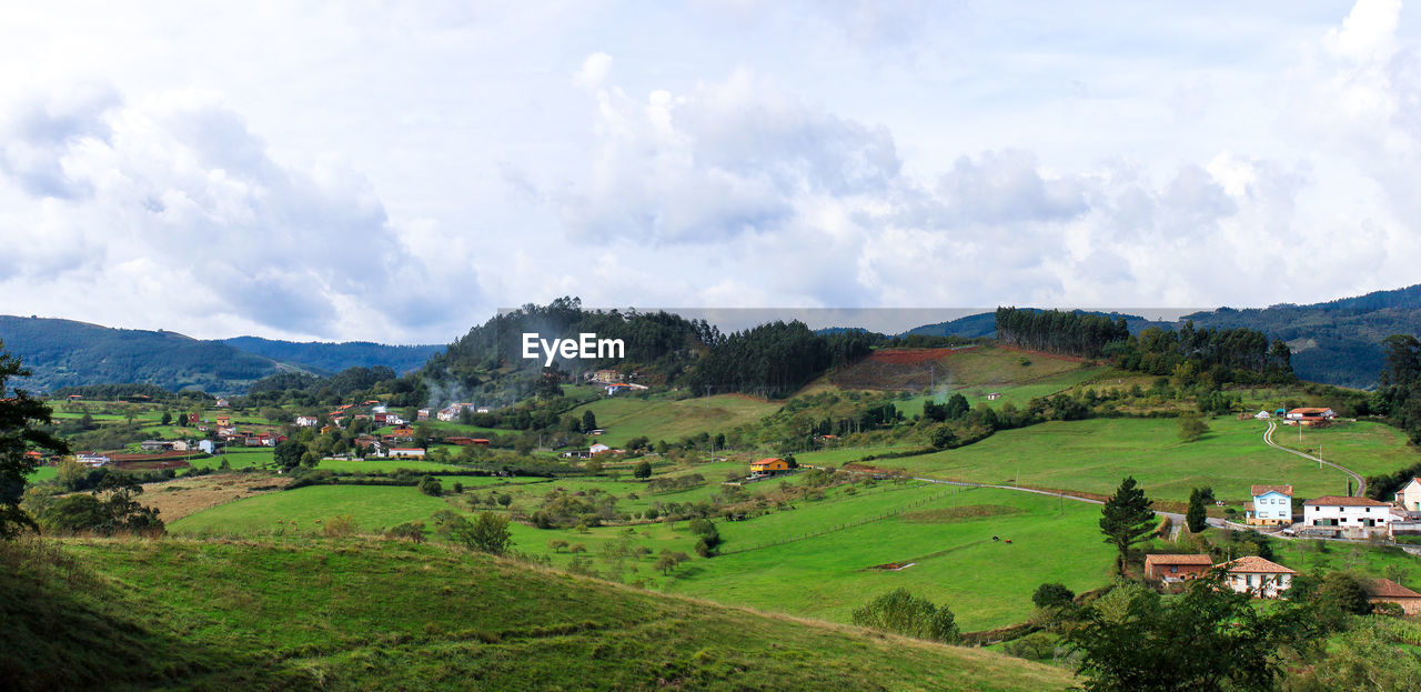 Scenic view of green hill against cloudy sky