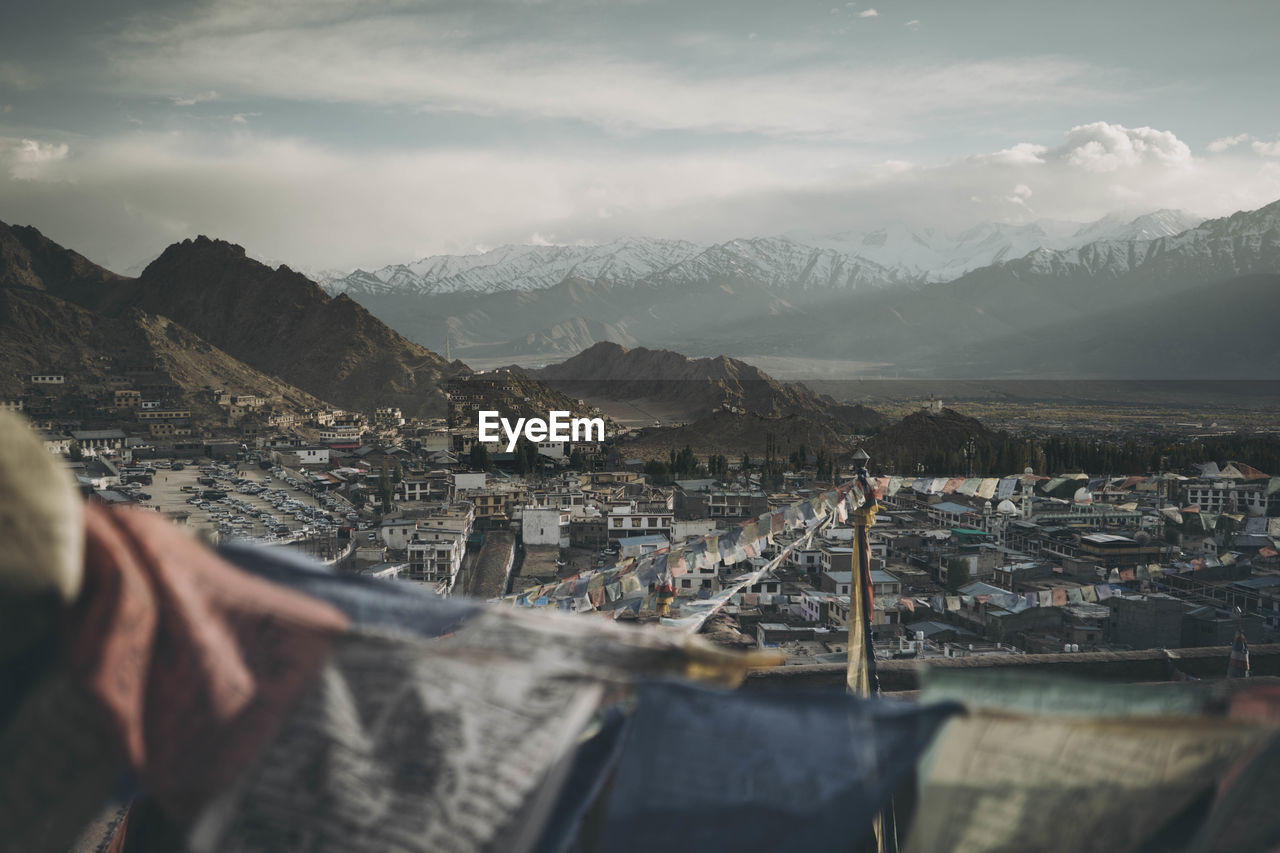 High angle view of buildings and mountains against cloudy sky