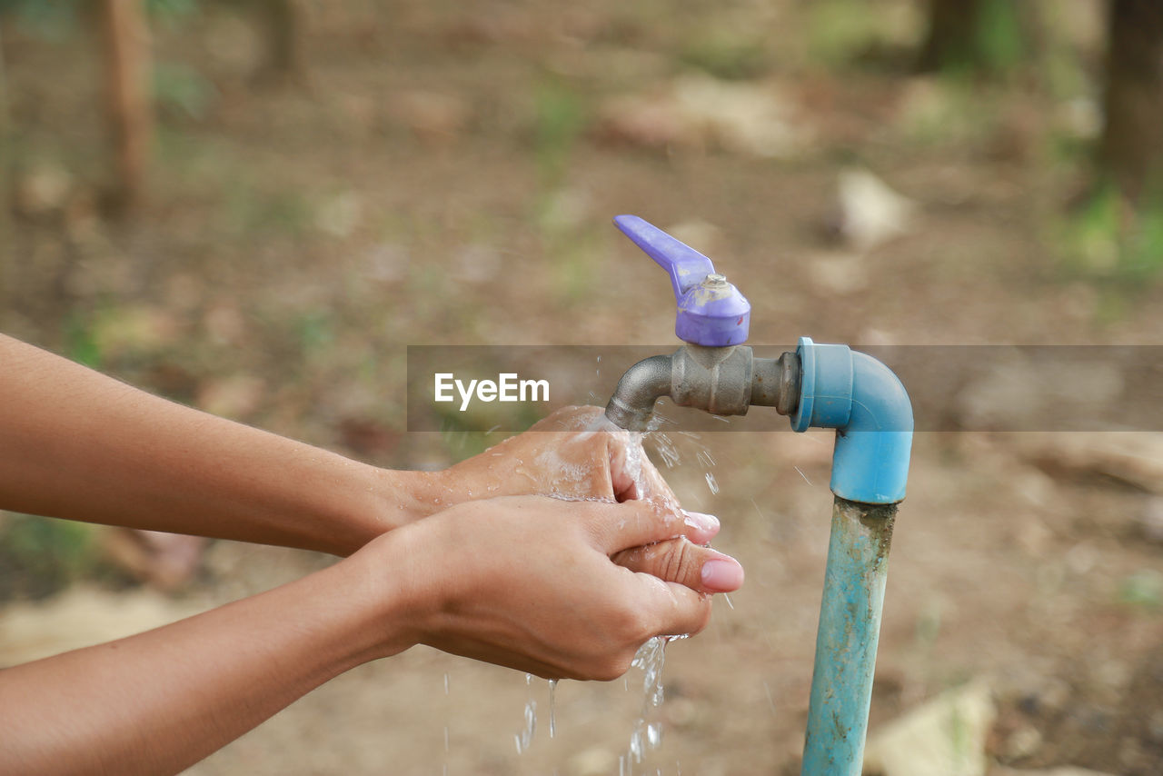 Cropped image of person washing hands at faucet