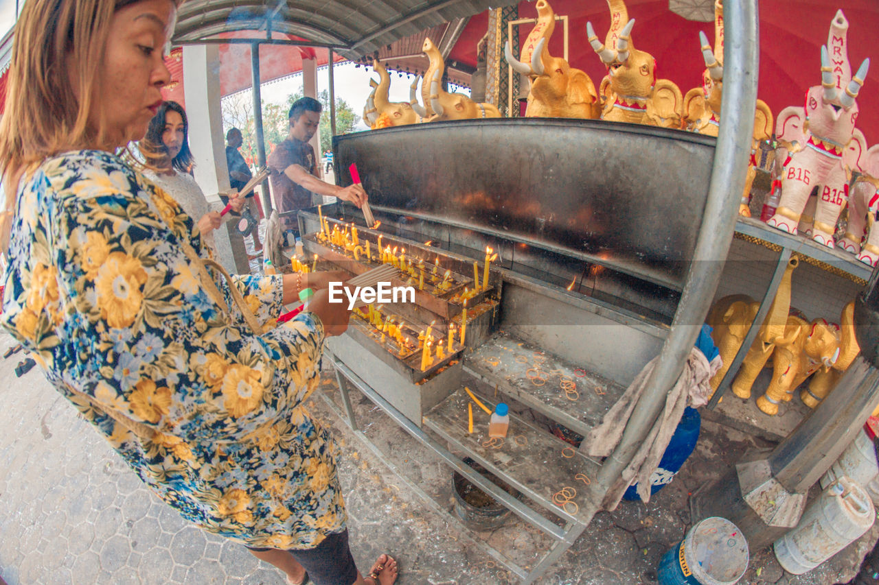 SIDE VIEW OF WOMAN PREPARING FOOD IN MARKET