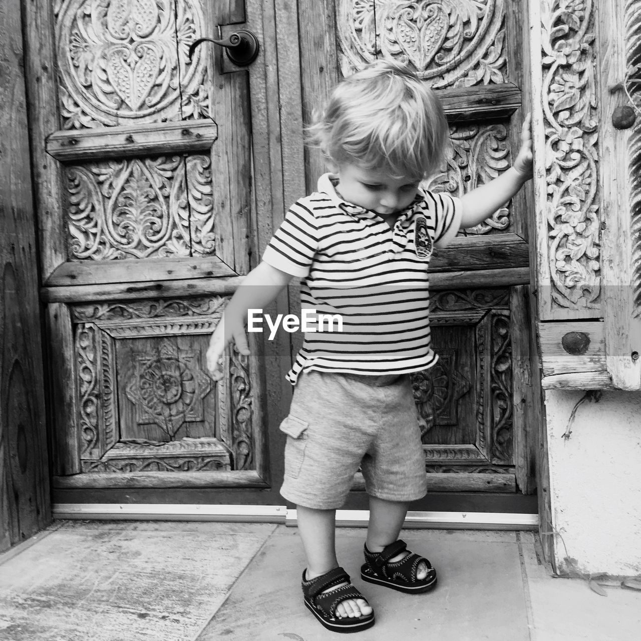 Cute boy standing outside closed door