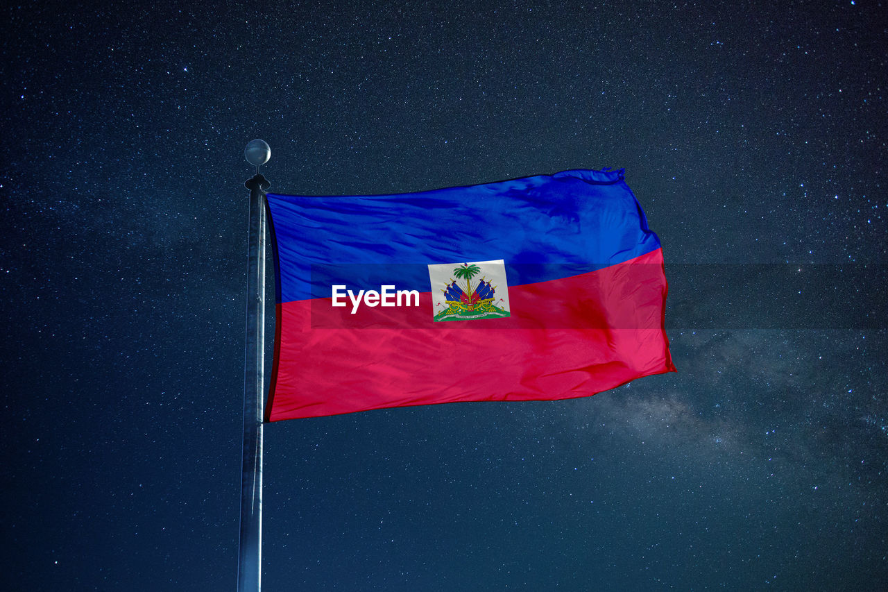 Low angle view of haiti flag against star field sky