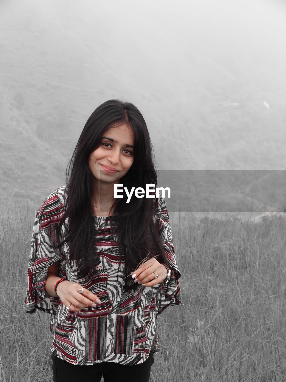 Portrait of smiling young woman standing against the hill