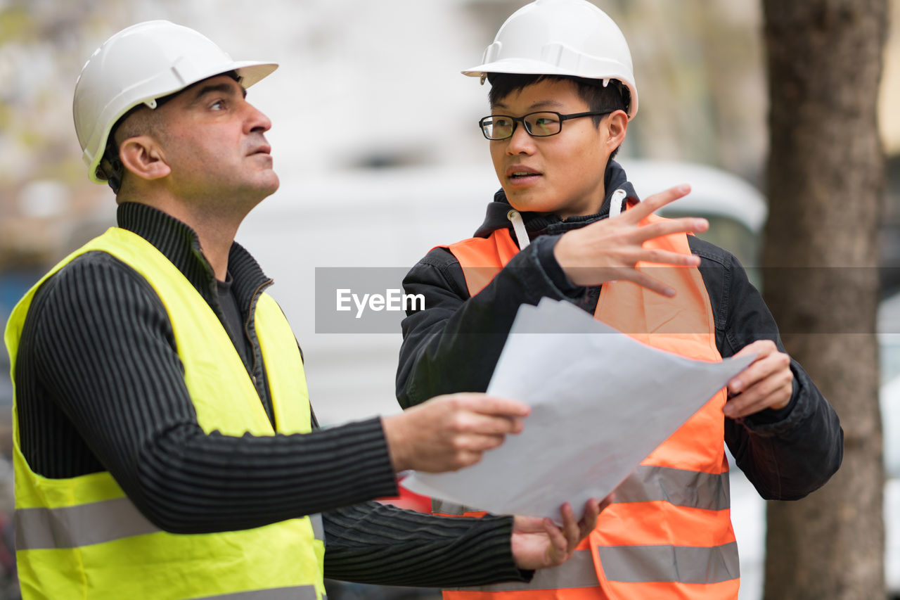 Engineers discussing while standing at construction site