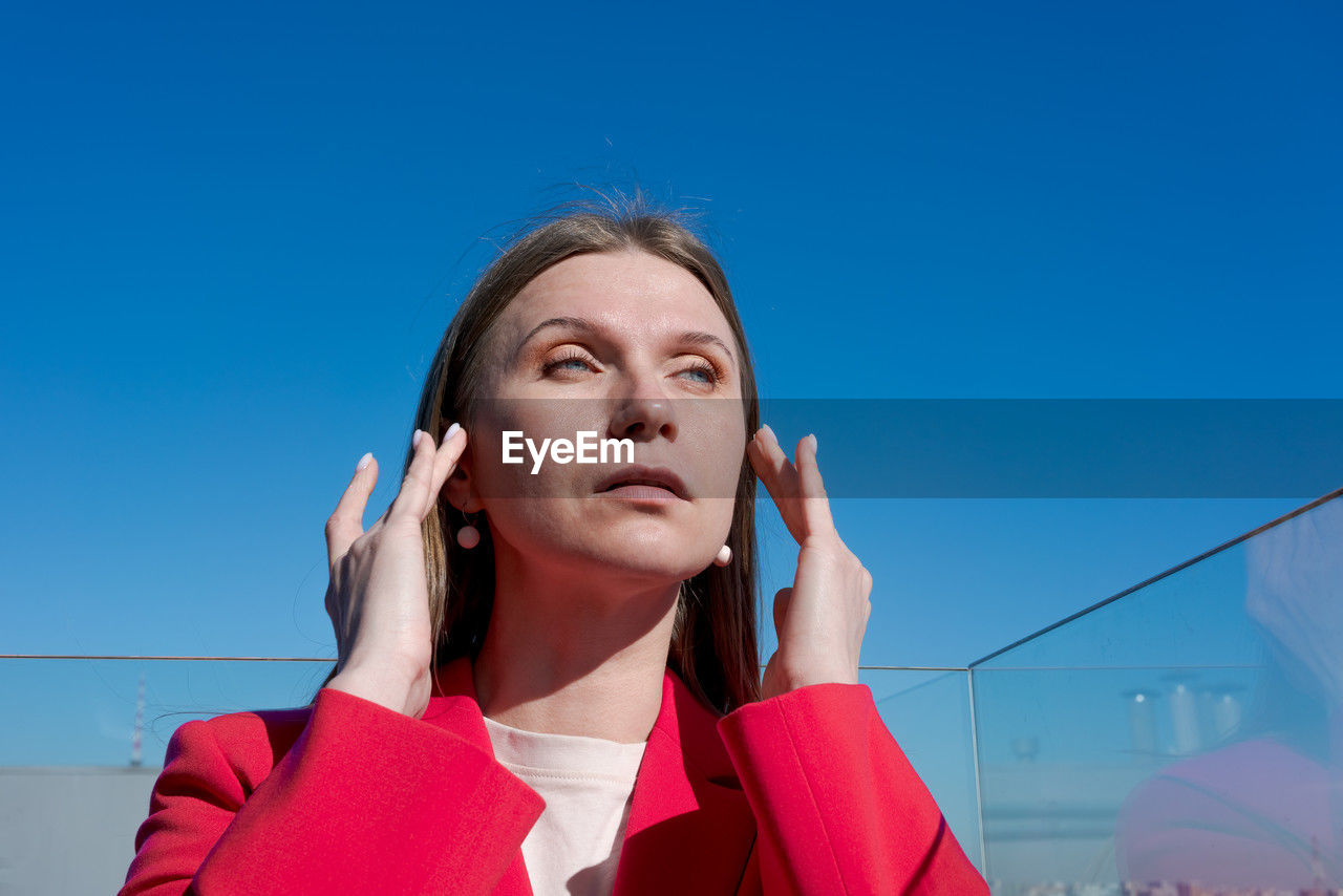 women, adult, one person, blue, telephone, using phone, portrait, sky, technology, mobile phone, wireless technology, looking, communication, headshot, copy space, listening, young adult, businesswoman, female, person, clear sky, emotion, front view, business, looking away, low angle view, day, smartphone, clothing, portable information device, lifestyles, contemplation, nature, city, holding, standing, outdoors, human face, architecture, red, looking up, brown hair, talking