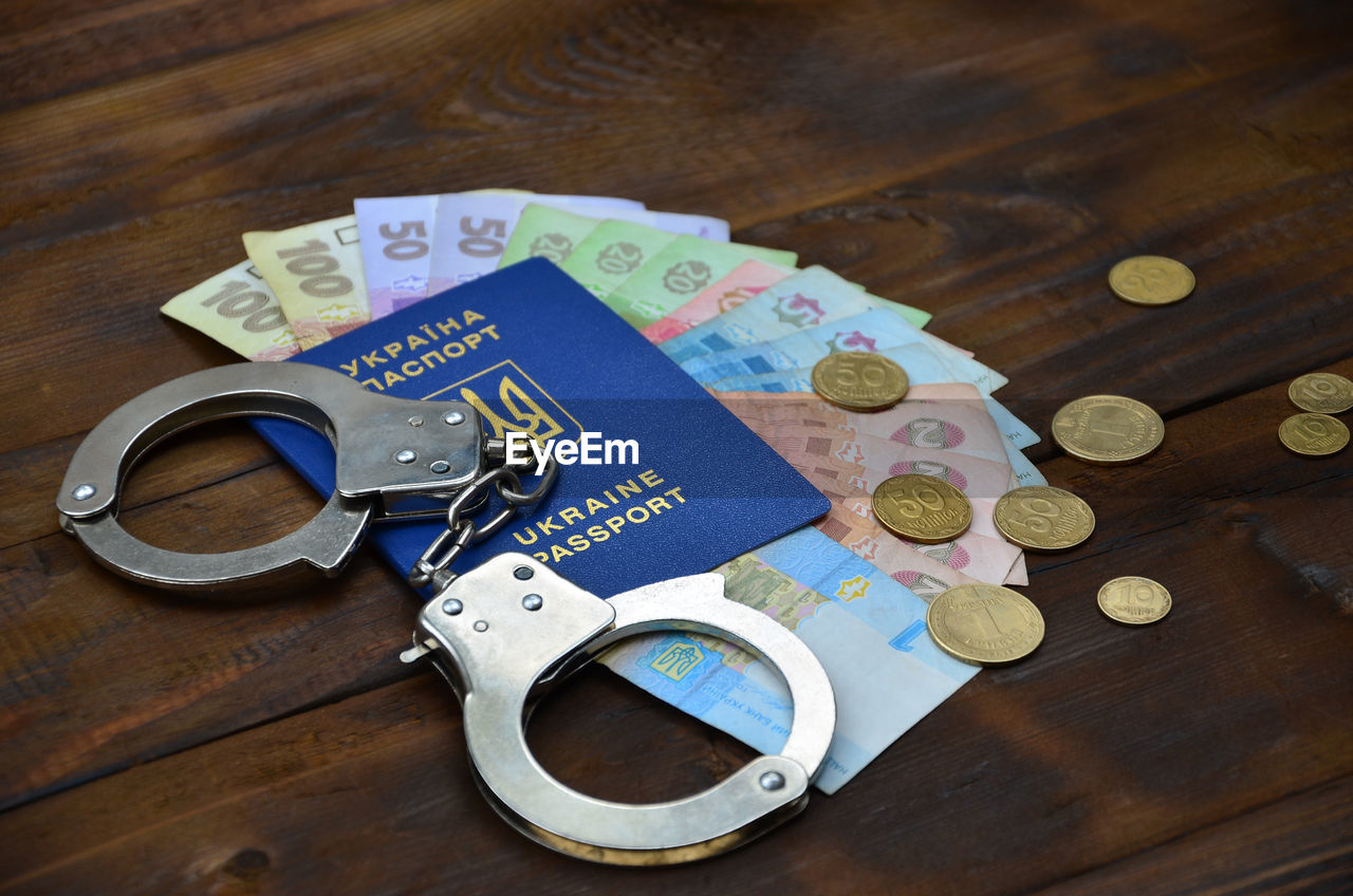 High angle view of handcuffs with passport and currency on table