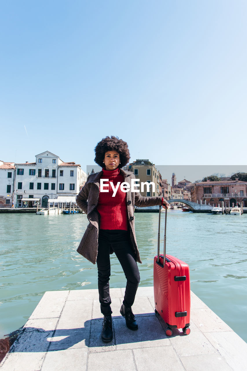 Young black woman holding luggage travel bag